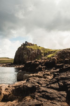 Rocky coast among tranquil ocean water in sunny day