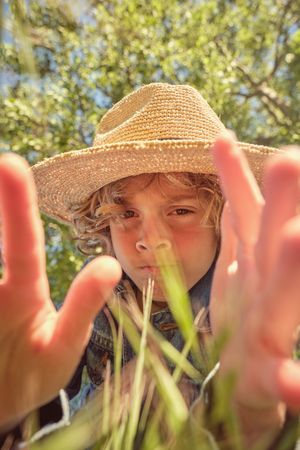 Little boy in straw hat looking at camera on sunny day