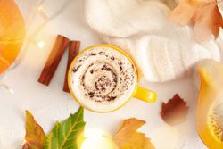 Composition with cup of pumpkin latte on light background