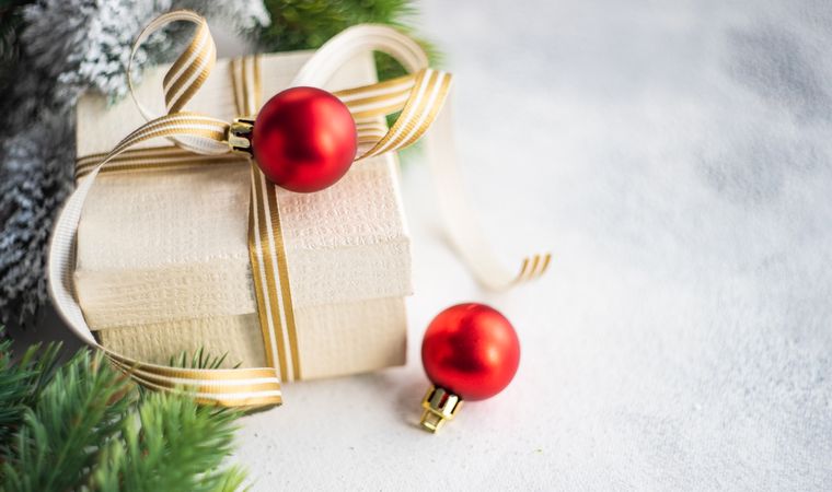 Christmas present with gold ribbon and red bauble on marble counter