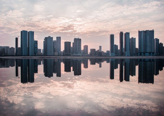 Sharjah city skyline reflection on water at sunset in UAE