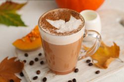 Composition with glass cup of pumpkin latte on light background