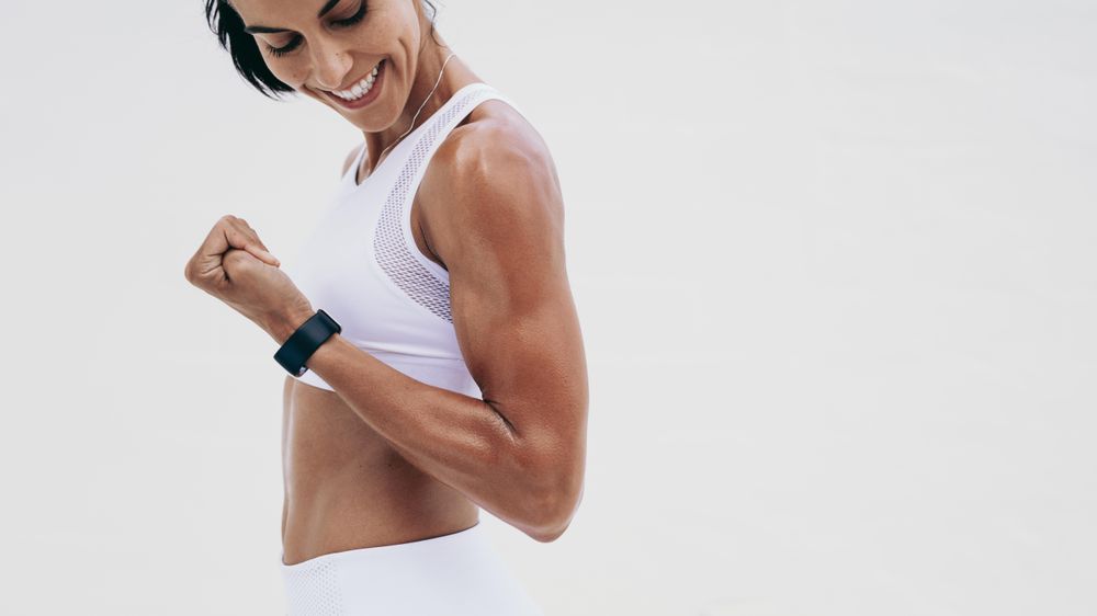 Smiling Fit Woman Showing Bicep Stock Photo, Picture and Royalty