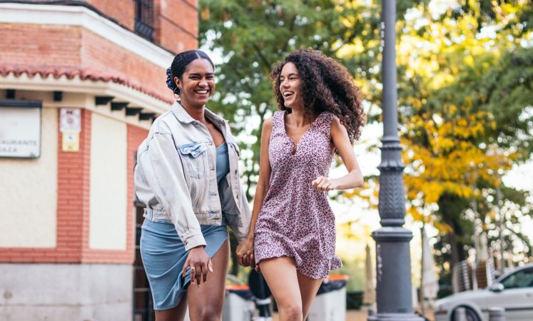 Lesbian couple walking down the street, holding hands.