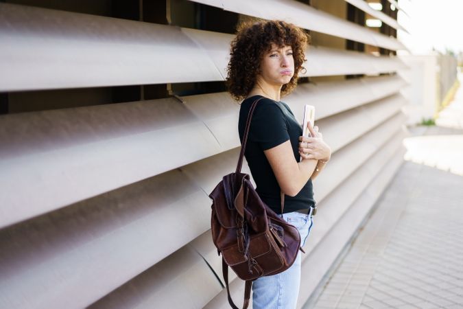 A Young Woman with Beautiful Curly Hair is Leaning Against a Stylish Modern Wall