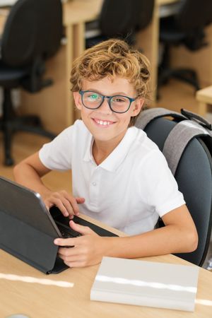 Delighted schoolboy using tablet in classroom