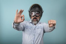 Portrait of a hipster biker pretending to ride a motorcycle against blue background