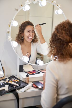 Happy woman applying makeup and laughing