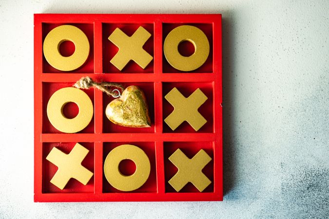 St. Valentine day card concept with gold heart ornament in center of tic-tac-toe game