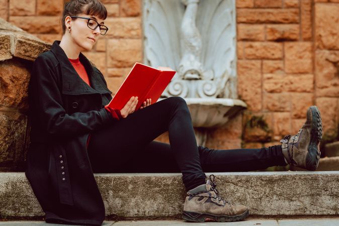 Young woman reading book on steps