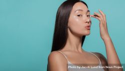 Woman applying beauty cream on her face 0JVXK0