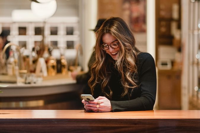Cheerful female using smartphone in cafe