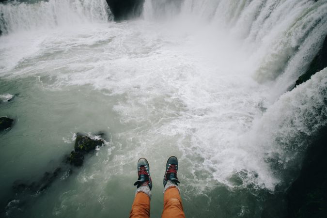 Hiker’s legs hanging over waterfall