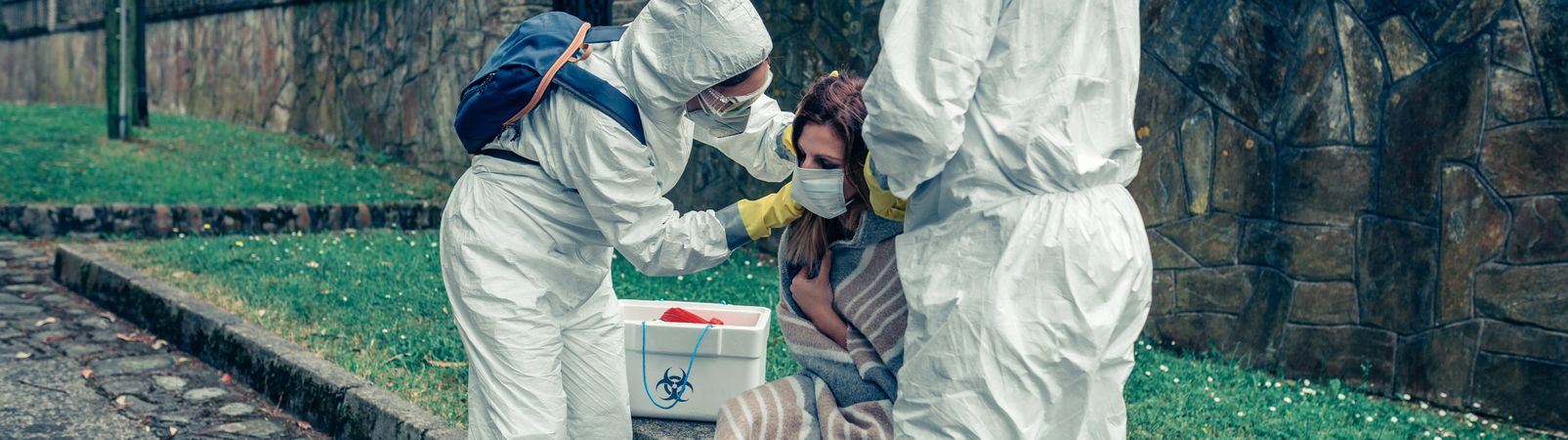 Doctors putting protective mask on woman infected with a virus