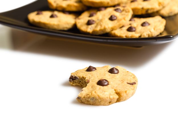 Chocolate chip cookie with a bite and pile of cookies in a plate on the background