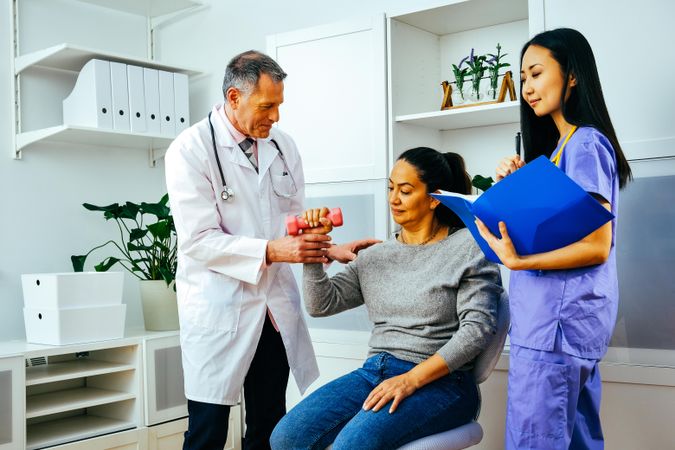 Content doctor and physiotherapist helping patient work through arm rehab exercises