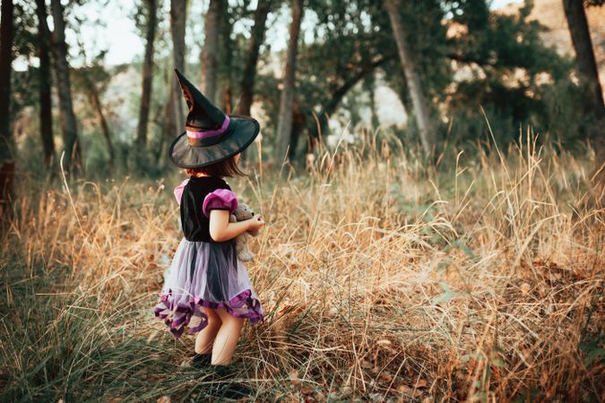 Girl looking into the forest dressed in witch costume