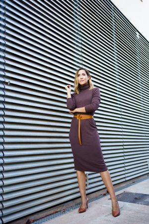 Woman in chic dress next to metal wall