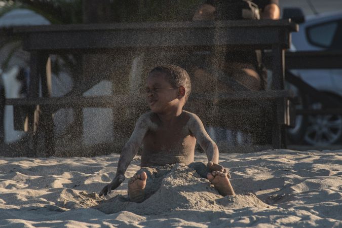 Young boy playing with sand on the beach