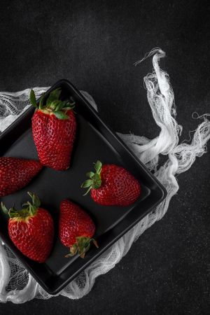 Red and fresh strawberries flat lay in dark dish
