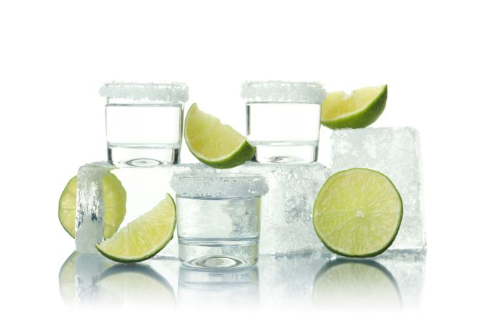 Stack of ice cubes with of limes and shot glasses