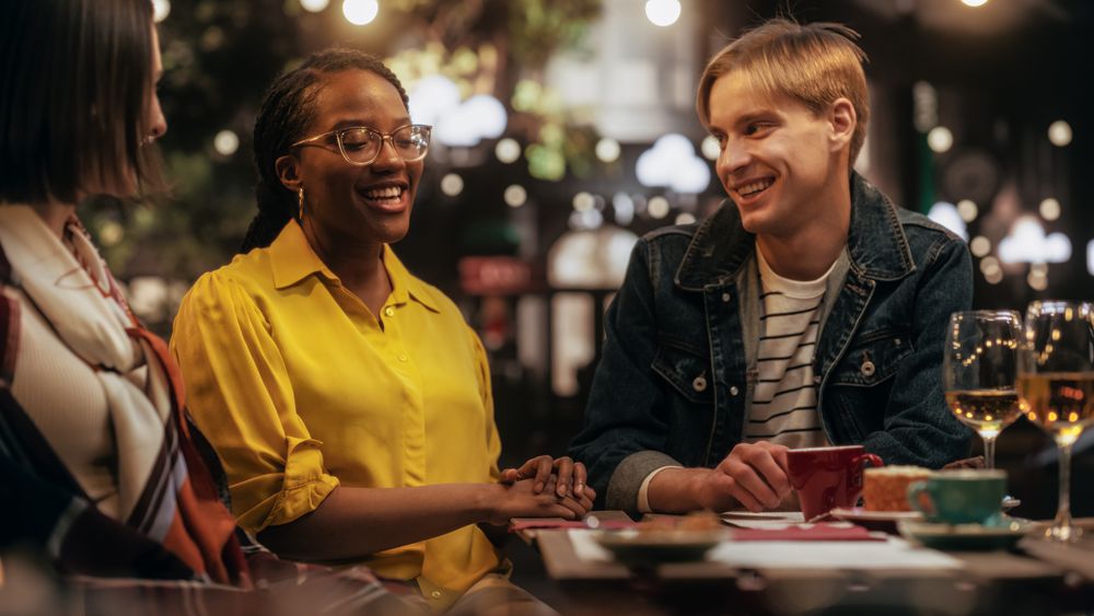 Young Men and Women Gathered in a Cafe in the Evening, Clapping and Celebrating the Success of a Friend