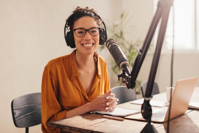Cheerful woman recording a podcast from home