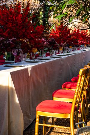 Formal dinner table with red seats and red floral arrangements