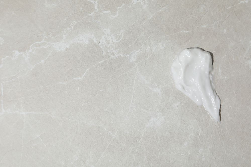 Cream drop on gray background, space for text