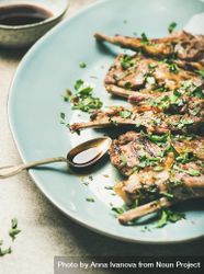 Plate of grilled lamb chops with parsley garnish on light blue plate 48Mjvb