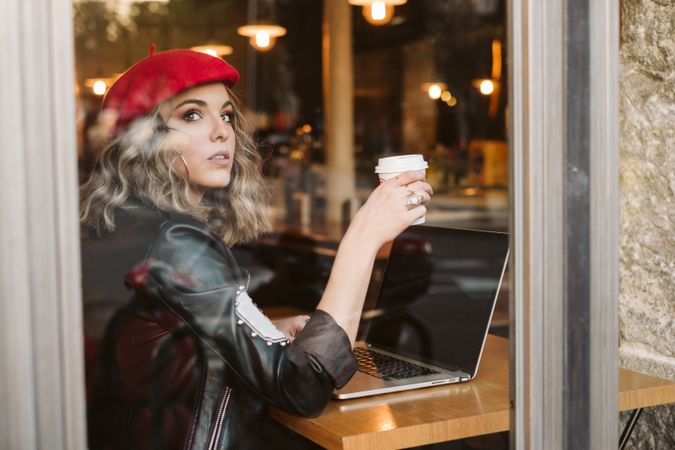 Dreamy woman using laptop in cafe