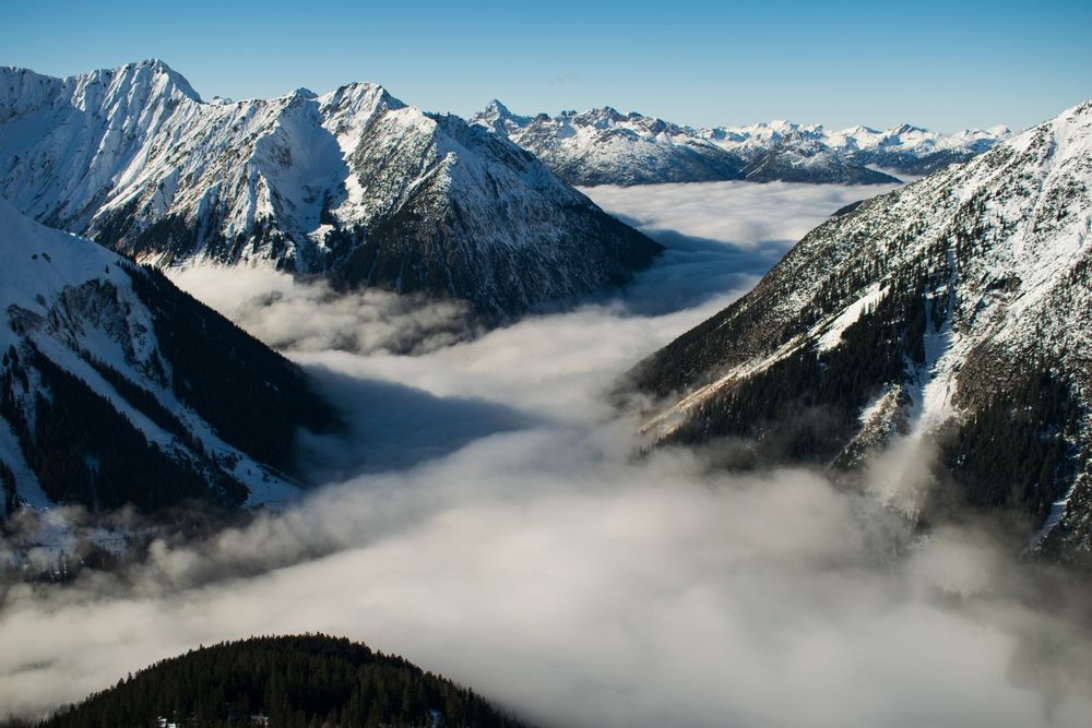Sea of clouds between snow covered mountains