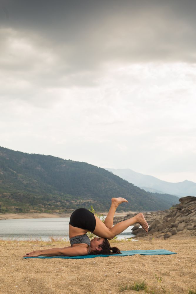 Woman practicing yoga outdoors near water