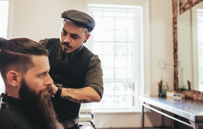 Stylish barber giving haircut to client