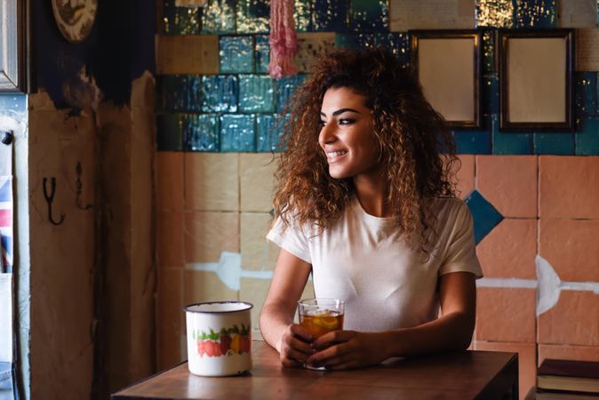 Arab woman in casual clothes drinking a soda in tiled restaurant