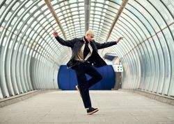Fashionable young man dancing in a long glass corridor