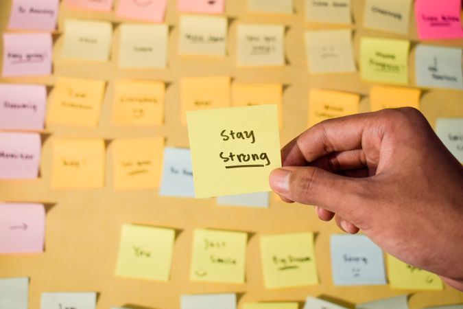 Hand hold sticky notes with words stay strong
