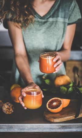 Woman holding two glasses with freshly squeezed blood orange juice
