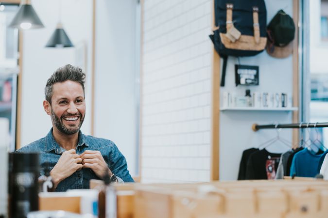 Man looking at mirror and touching beard in salon