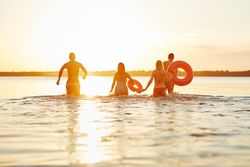Multi-ethnic group of friends wadding through the water in swimsuits