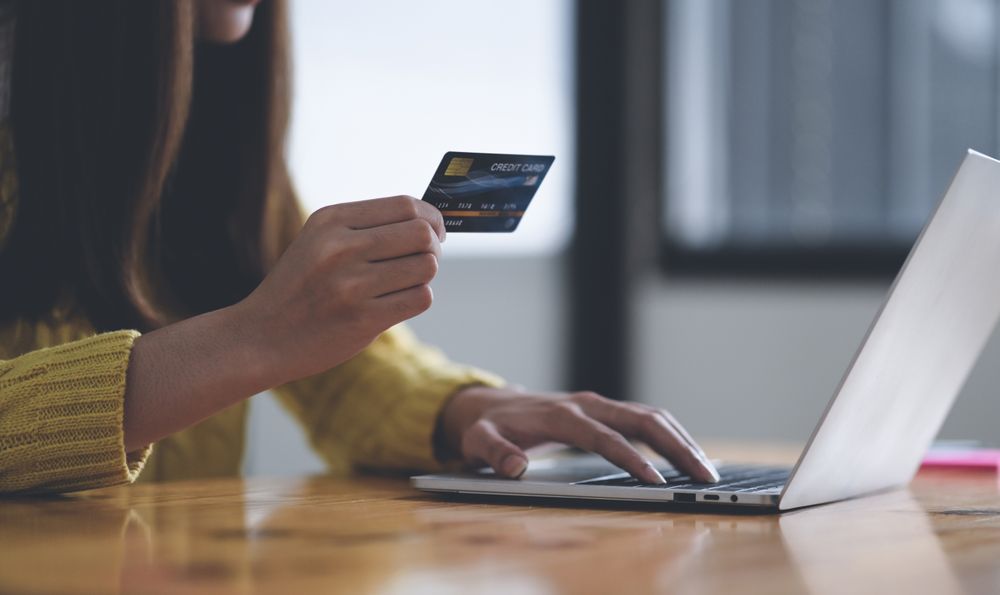 Young woman using laptop computer and holding credit card