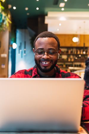 Smiling Black man working on laptop in cafe