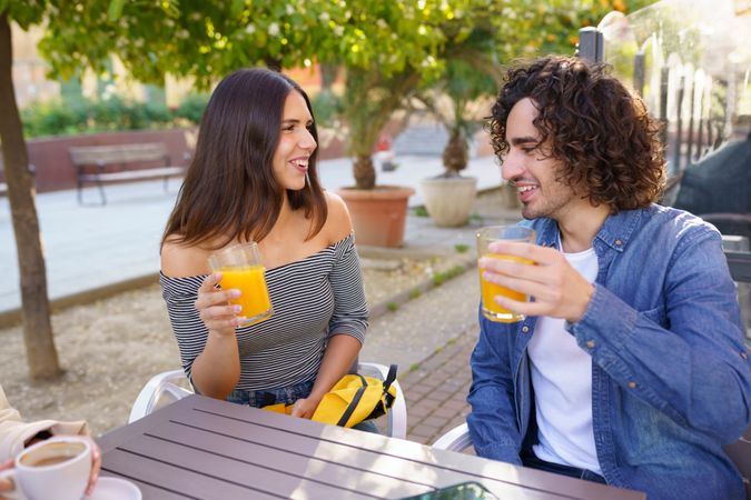Man and woman chatting with their orange juice outside