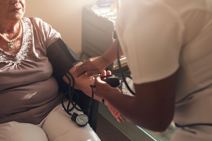 Nurse giving a mature female patient a blood pressure test