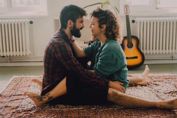 Loving couple embracing while sitting on apartment floor