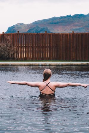 Woman in pool near sea and hills on shore