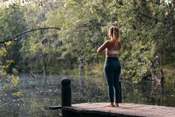 Woman in sportswear doing yoga outdoors near a lake