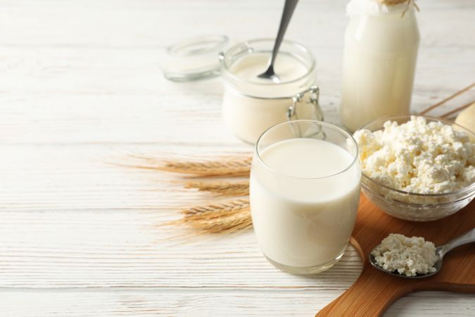 Spikelets of wheat, dairy products and board on wood background, copy space