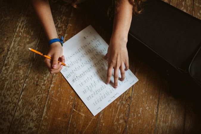 Student filling in sheet music with music notes
