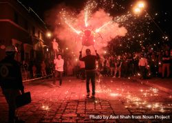 Man holding figure with fireworks at street festival 0KwvA0